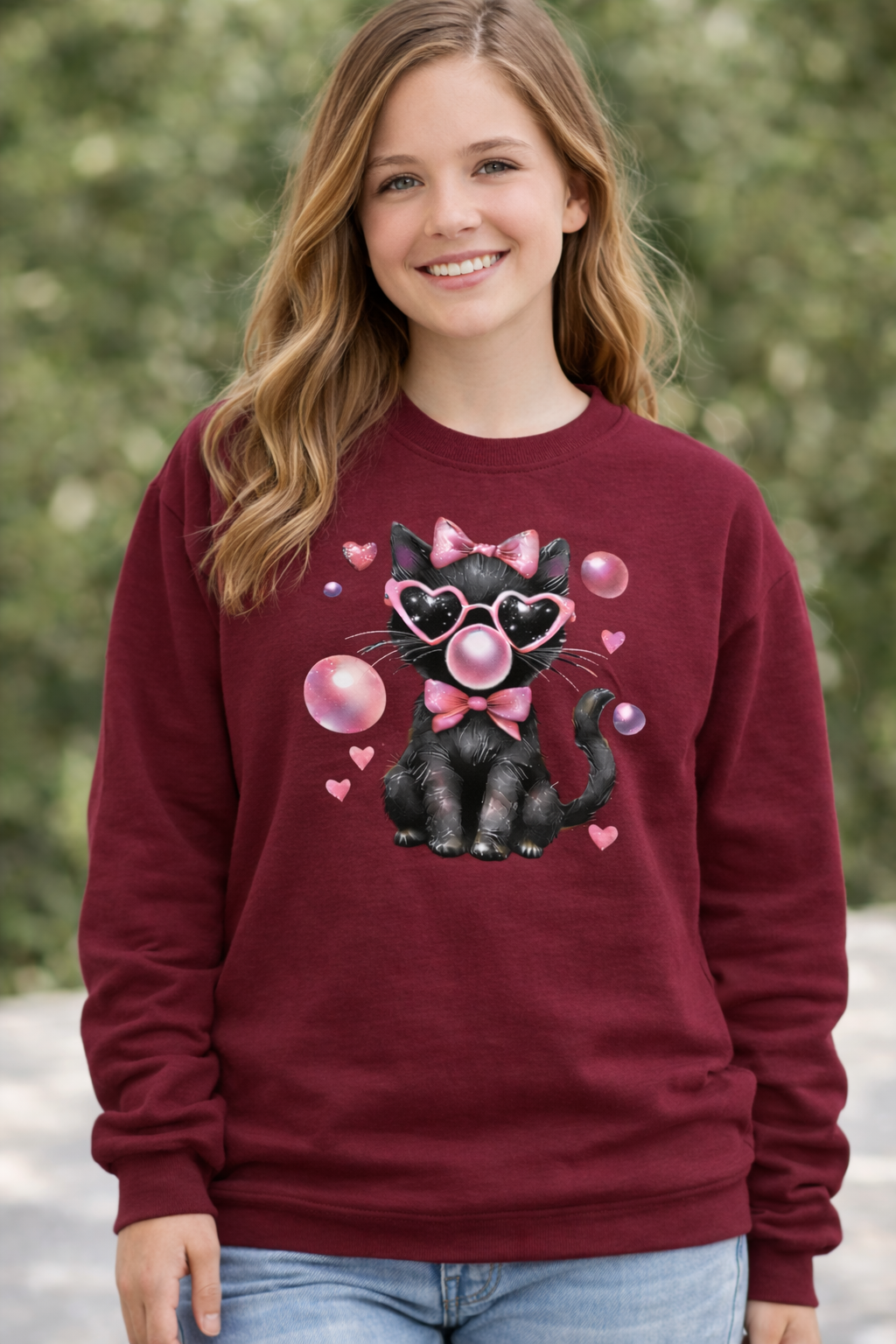 Person wearing a maroon sweatshirt with a black cat design, surrounded by hearts and bubbles.