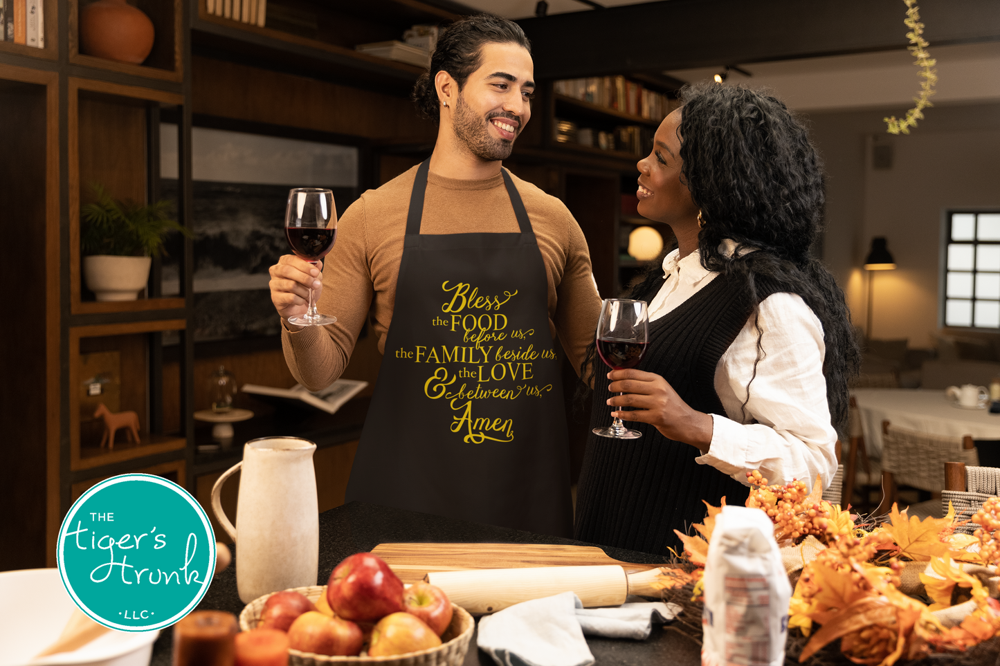 Two people in aprons standing in a kitchen, holding wine glasses.