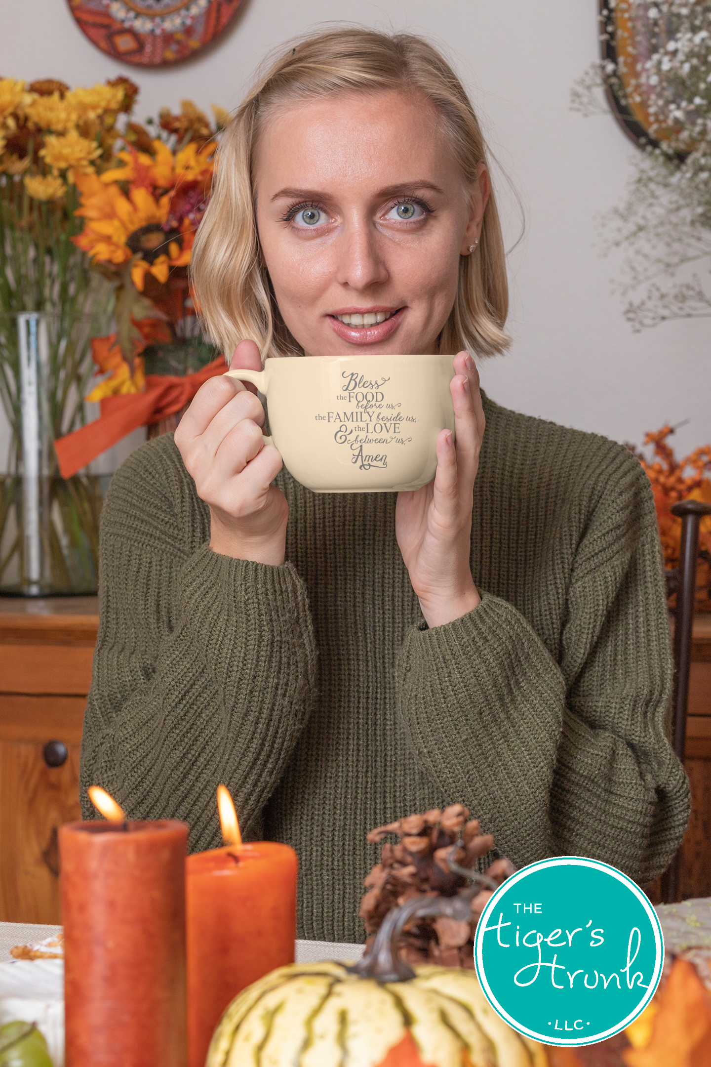 Woman holding a mug with text in a cozy indoor setting with pumpkins and candles.