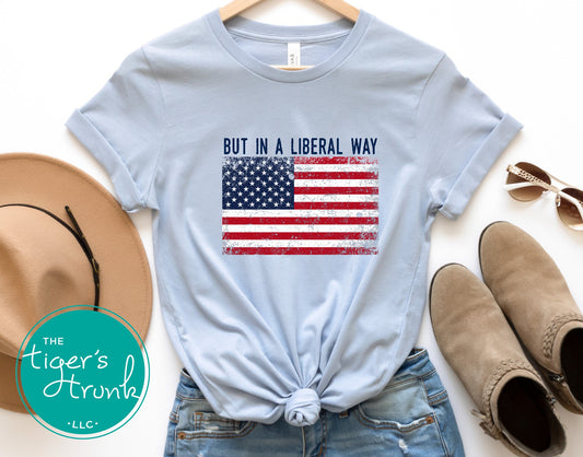 Light blue graphic shirt with full size bold American flag and the phrase But in a Liberal Way, progressive political tee for civic-minded patriots
