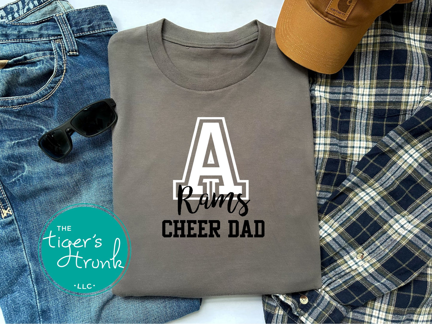 Gray t-shirt with 'A Rams Cheer Dad' text on a plaid fabric background