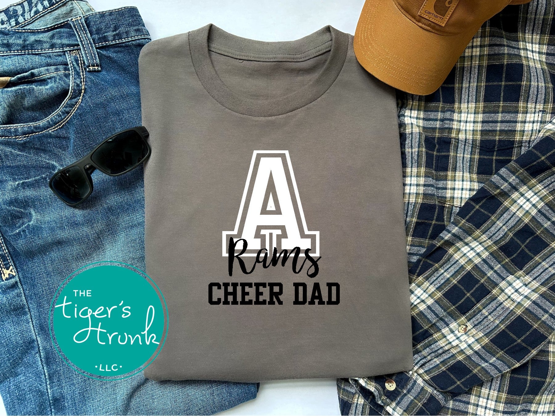 Gray t-shirt with 'A Rams Cheer Dad' text on a plaid fabric background