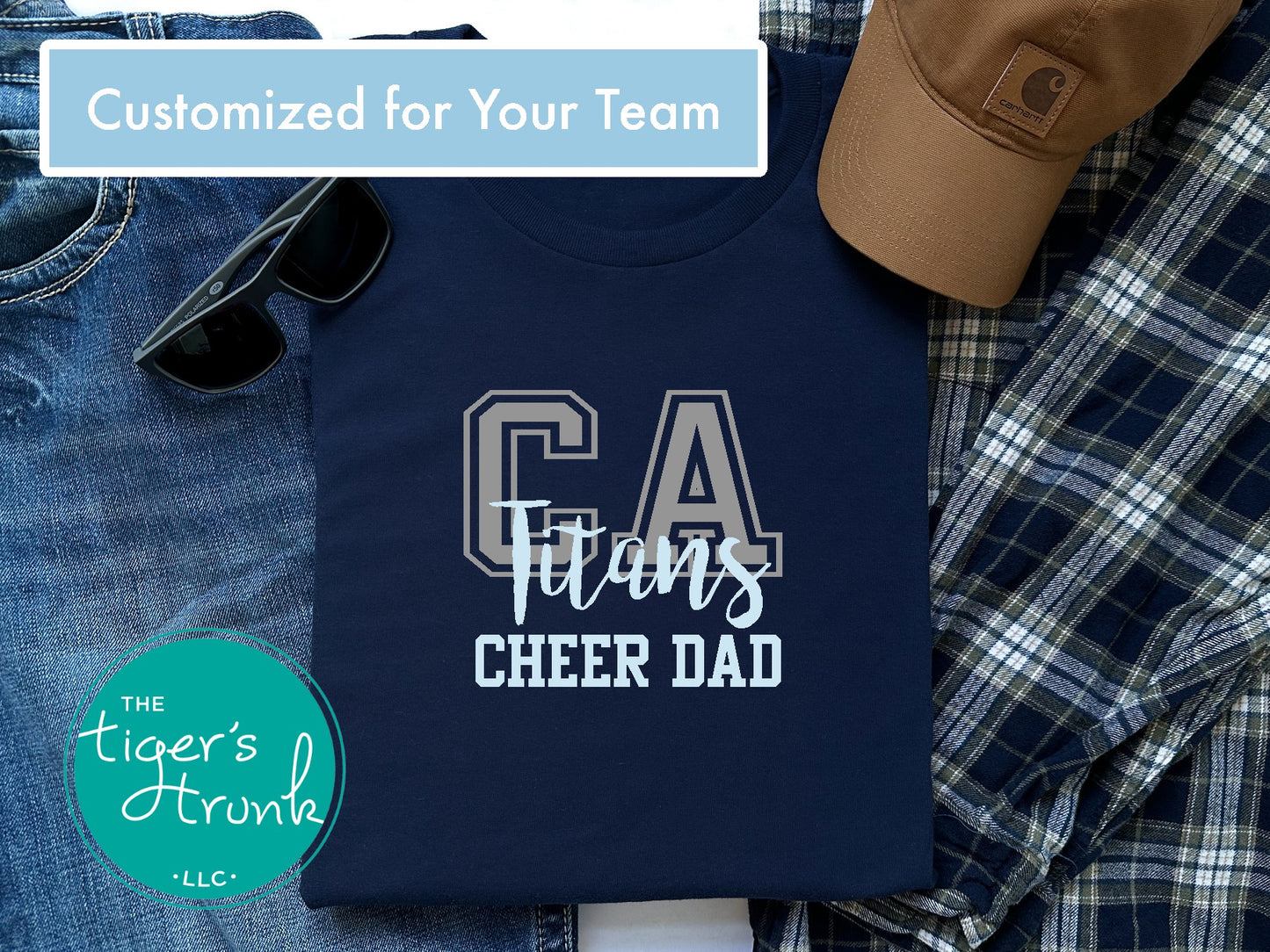 Navy t-shirt with 'CA Titans Cheer Dad' text, sunglasses, jeans, and a cap on a checkered fabric background.