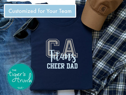 Navy t-shirt with 'CA Titans Cheer Dad' text, sunglasses, jeans, and a cap on a checkered fabric background.