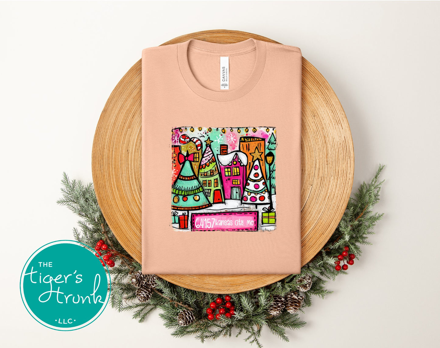 Peach Christmas town tee featuring festive village scene and personalized ZIP code 64157 Kansas City MO