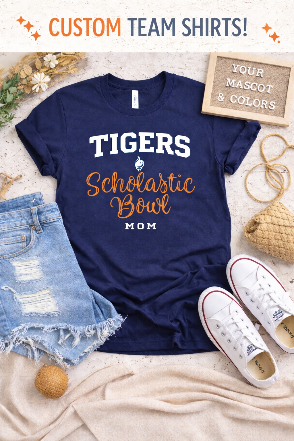 Navy blue t-shirt with 'Tigers Scholastic Bowl Mom' text, denim shorts, and white sneakers on a light background.