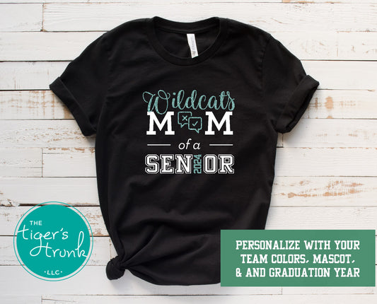 A black short-sleeve shirt with white text and graphics, featuring the phrase 'Wildcats Mom of a Senior' and the graduation year '2025'. The shirt is customizable with a mascot and graduation colors, and it has a logo at the bottom.