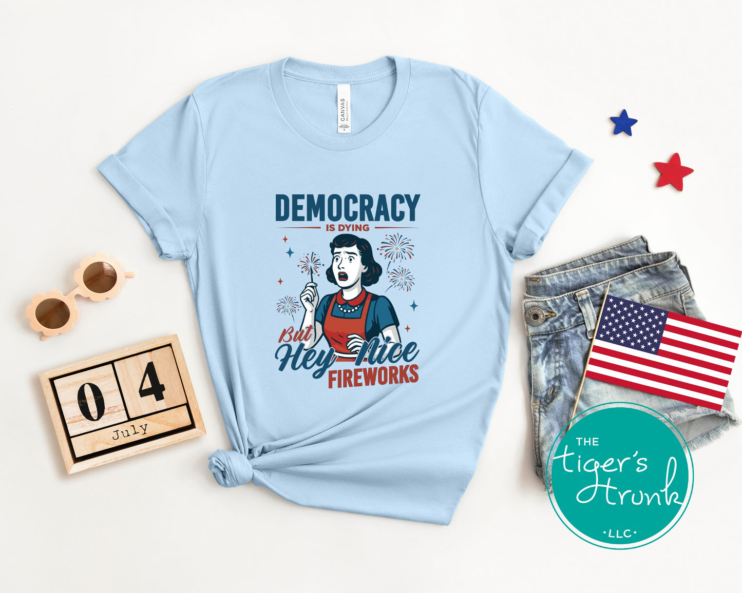Funny political t-shirt that reads Democracy Is Dying But Hey, Nice Fireworks, worn for sarcastic July Fourth cookouts