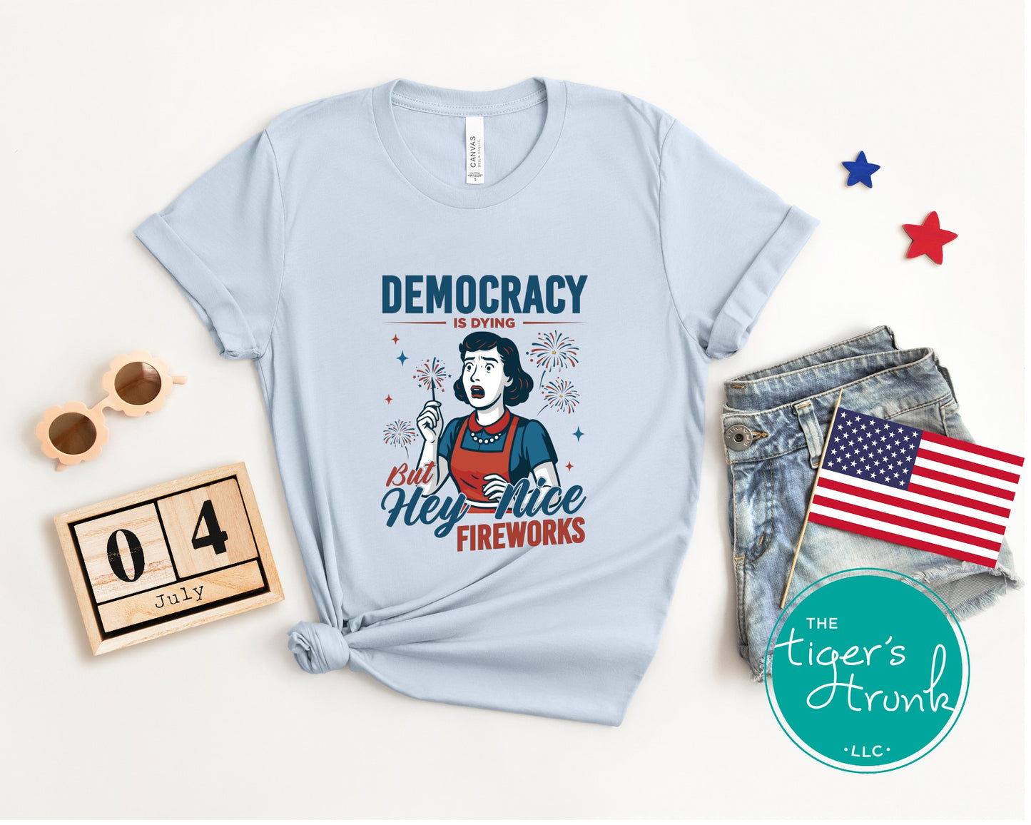 Funny political t-shirt that reads Democracy Is Dying But Hey, Nice Fireworks, worn for sarcastic July Fourth cookouts