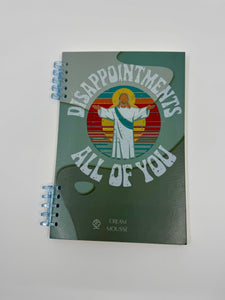 Blank lined journal with "Disappointments, All of You" on the cover alongside a graphic of Jesus.