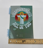 Blank lined journal with "Disappointments, All of You" on the cover alongside a graphic of Jesus.