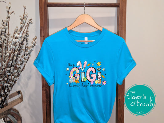 Easter t-shirt with "Gigi" in pastel spring print font including bunnies, florals, and Easter eggs, perfect for spring celebrations