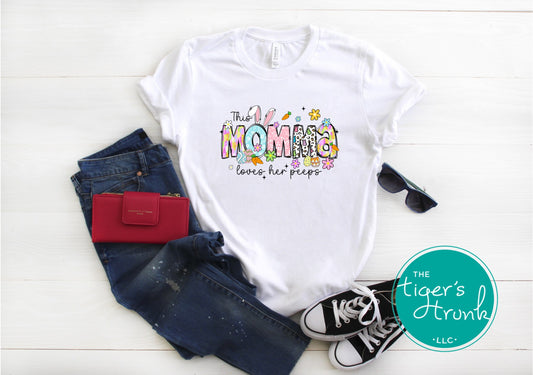 Easter t-shirt with "Momma" in colorful spring-themed font including bunnies, eggs, and florals, perfect for Easter gatherings
