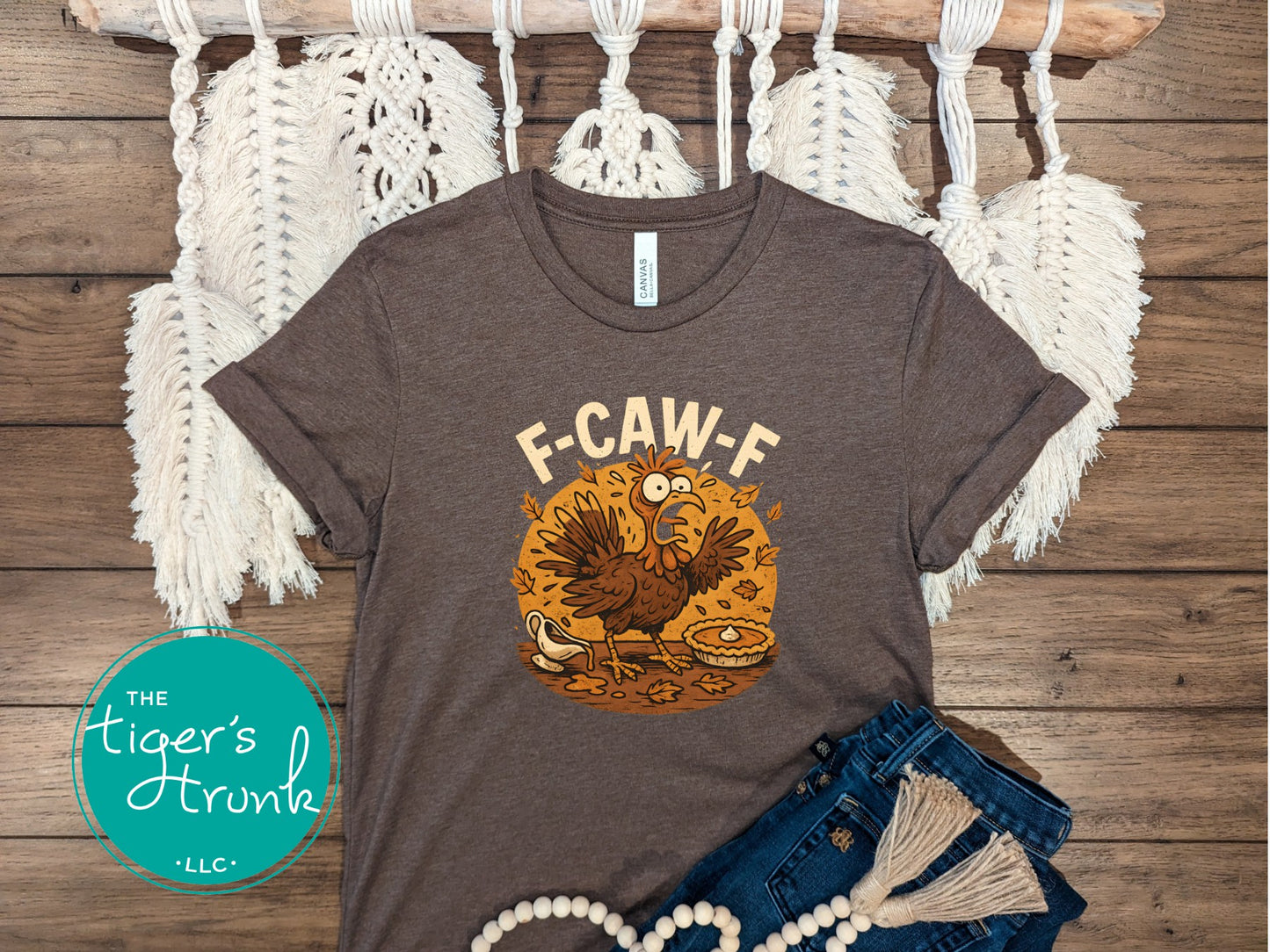 Brown t-shirt with a turkey graphic and 'F-CAW-F' text on a wooden surface with decorative elements.
