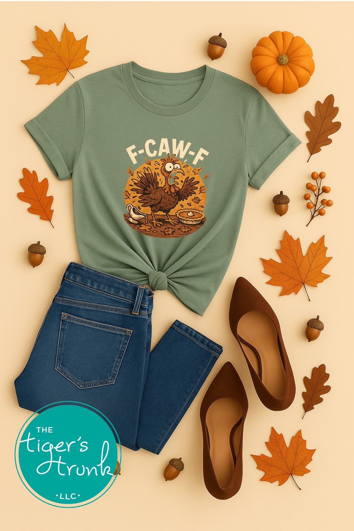 Green t-shirt with a turkey graphic and text, paired with jeans and shoes on a beige background with fall elements.