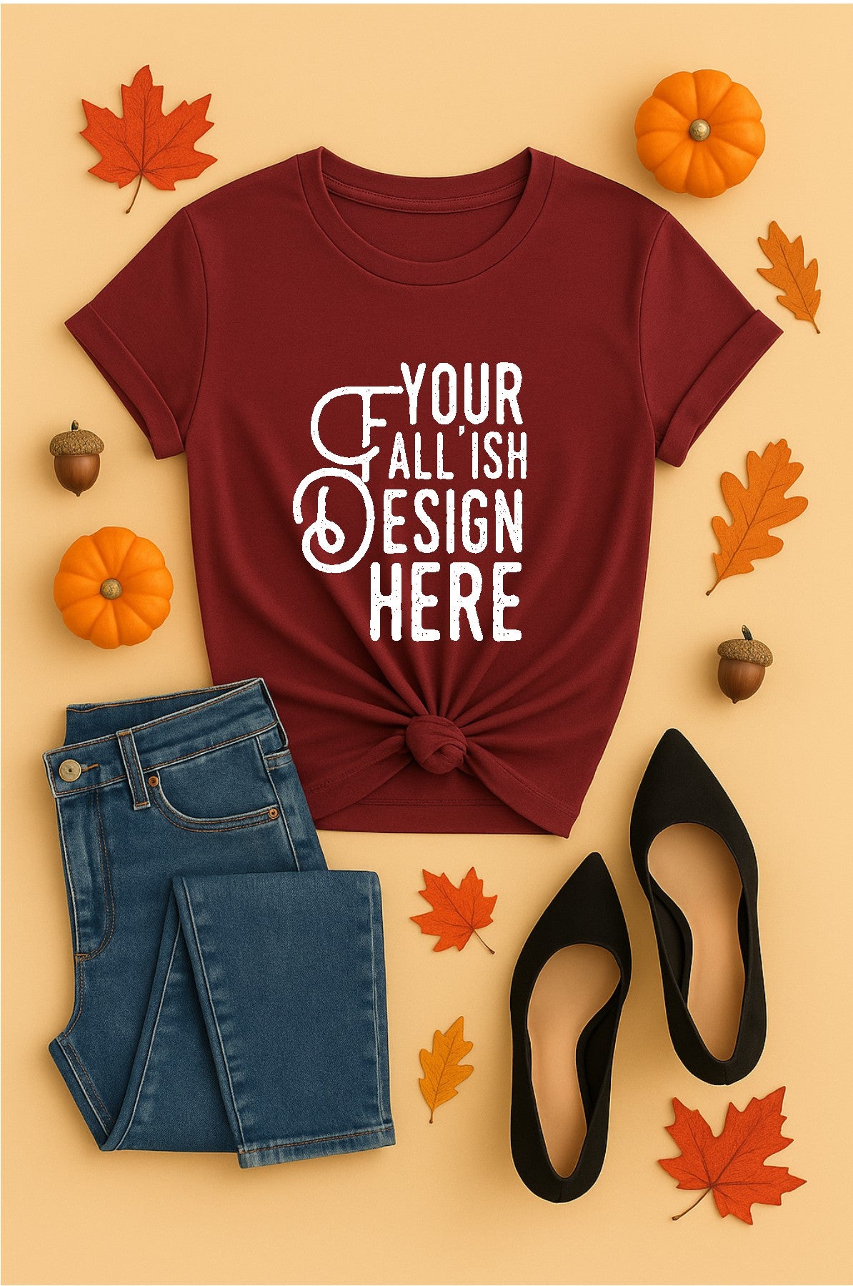 Maroon t-shirt with 'Your Fall Ish Design Here' text, jeans, black shoes, and fall-themed decor on a beige background.