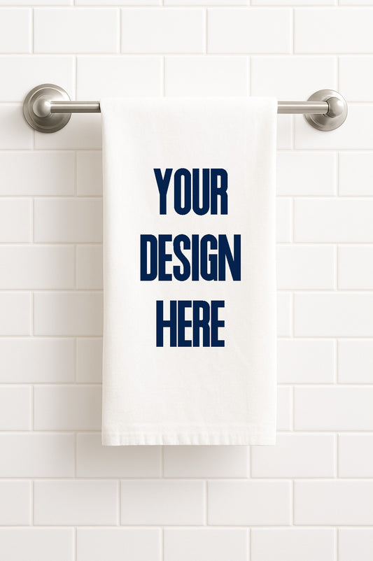 White towel with 'Your Design Here' text on a white tiled wall