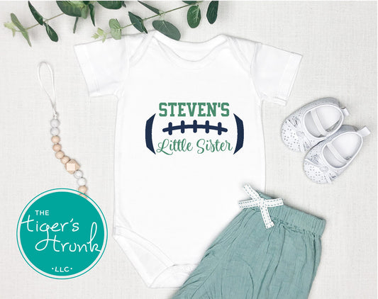Baby onesie with 'Steven's Little Sister' text, baby shoes, and green pants on a light background.