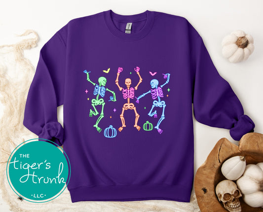 Purple sweatshirt with colorful skeleton design on a white background with pumpkins and skulls.