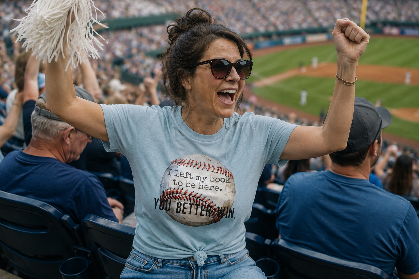 Woman cheering at a baseball game with pom-poms and sunglasses, wearing a t-shirt with a humorous message.