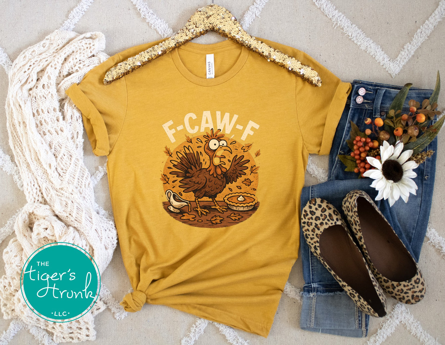 Yellow t-shirt with a rooster graphic and 'F-CAW-F' text, displayed with jeans and shoes on a textured surface.