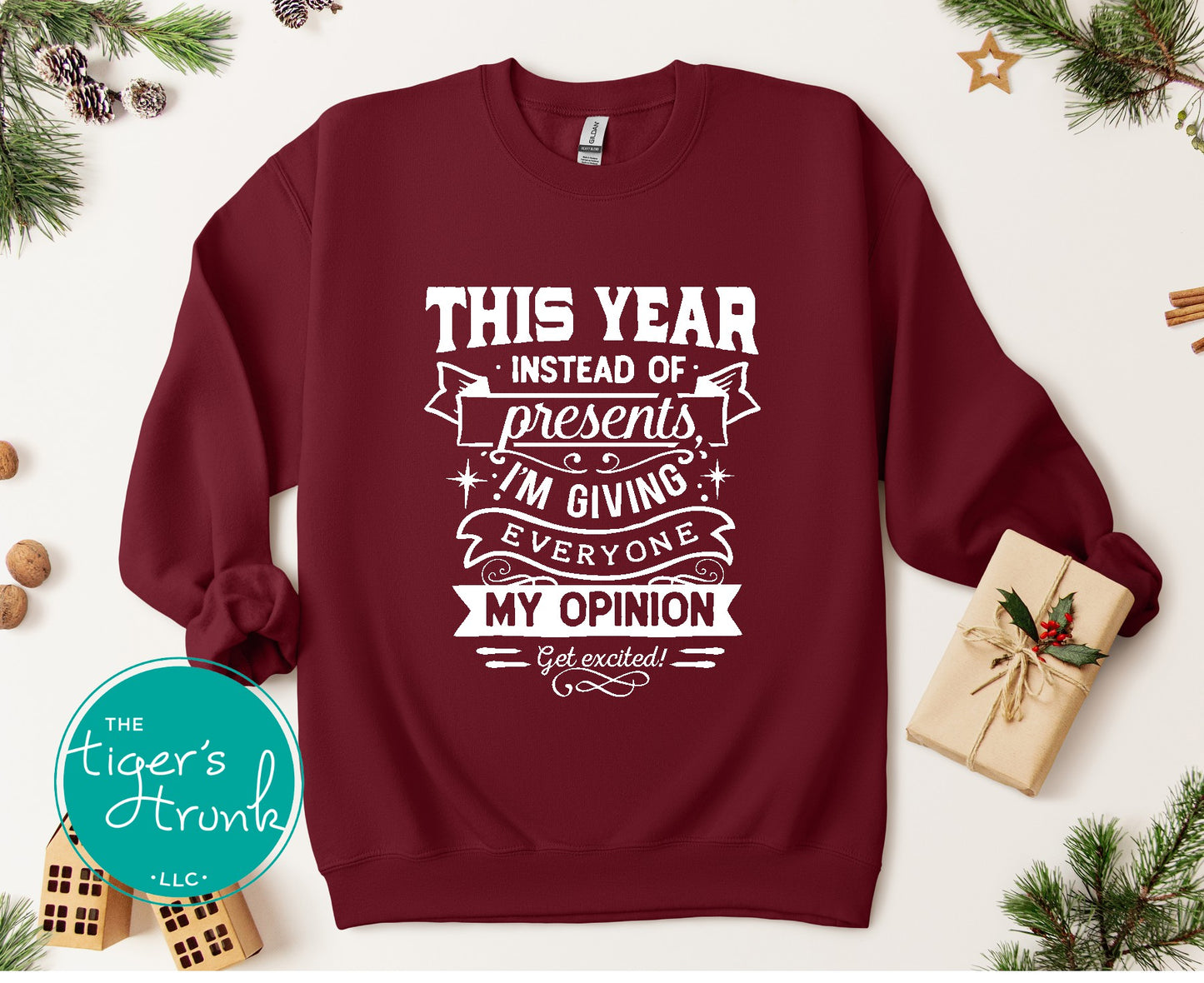 Maroon sweatshirt with white text on a festive background with Christmas decorations.