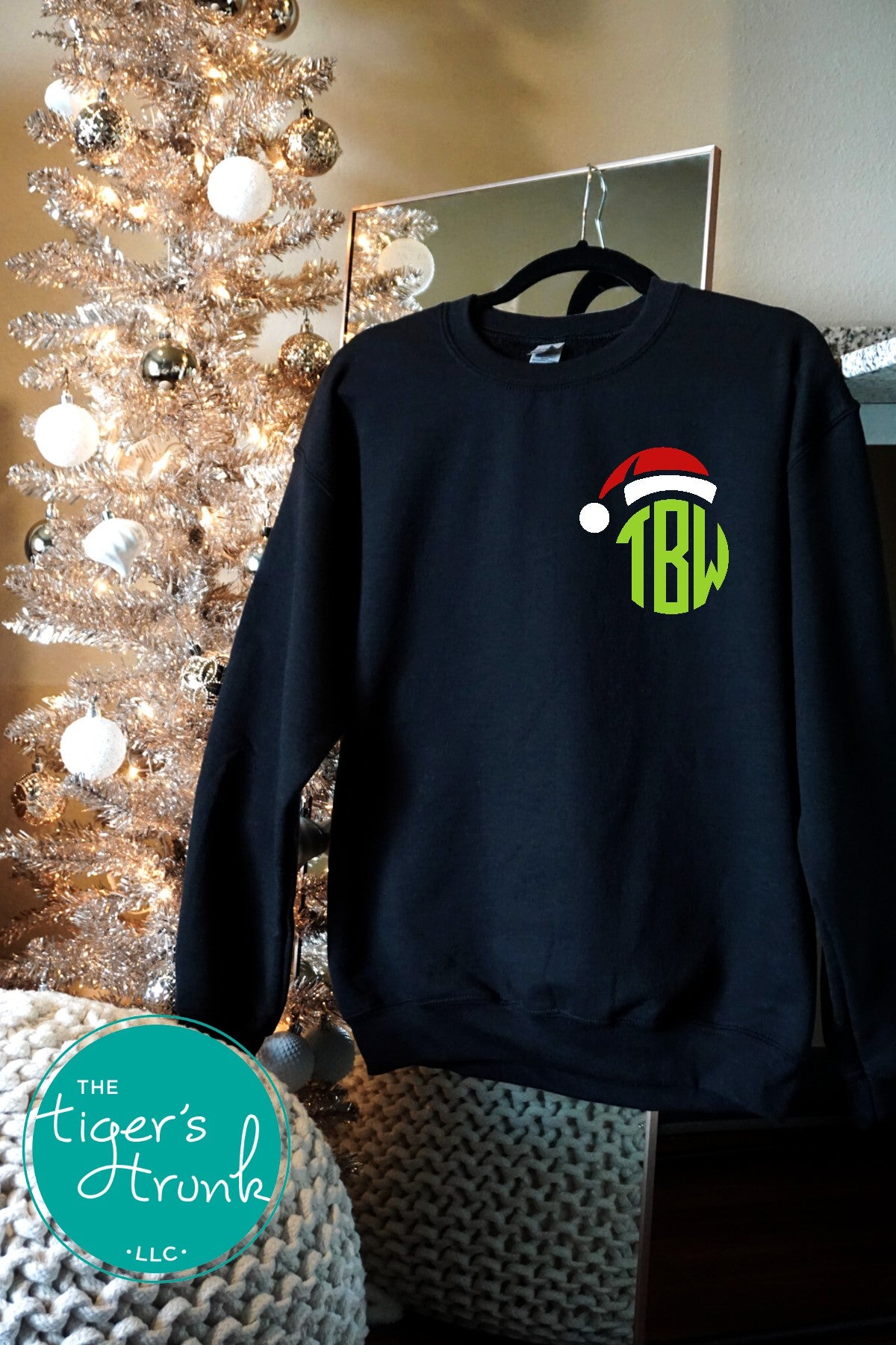 Black sweatshirt with a Christmas-themed design and 'TBW' monogram in front of a decorated Christmas tree.