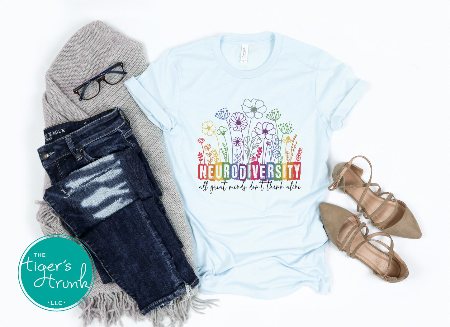 Ice blue neurodiversity shirt flatlay with jeans and neutral accessories