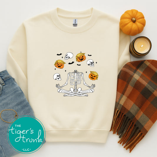 Beige sweatshirt with Halloween-themed design, surrounded by pumpkins, a candle, and plaid scarf on a white background.