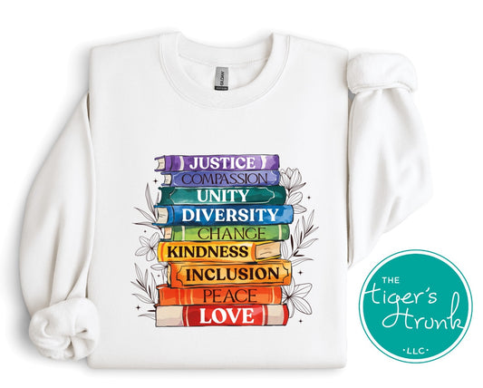 Sweatshirt with rainbow book spines labeled Justice, Compassion, Unity, Diversity, Kindness, Inclusion, Peace, and Love, LGBTQ+ Pride message