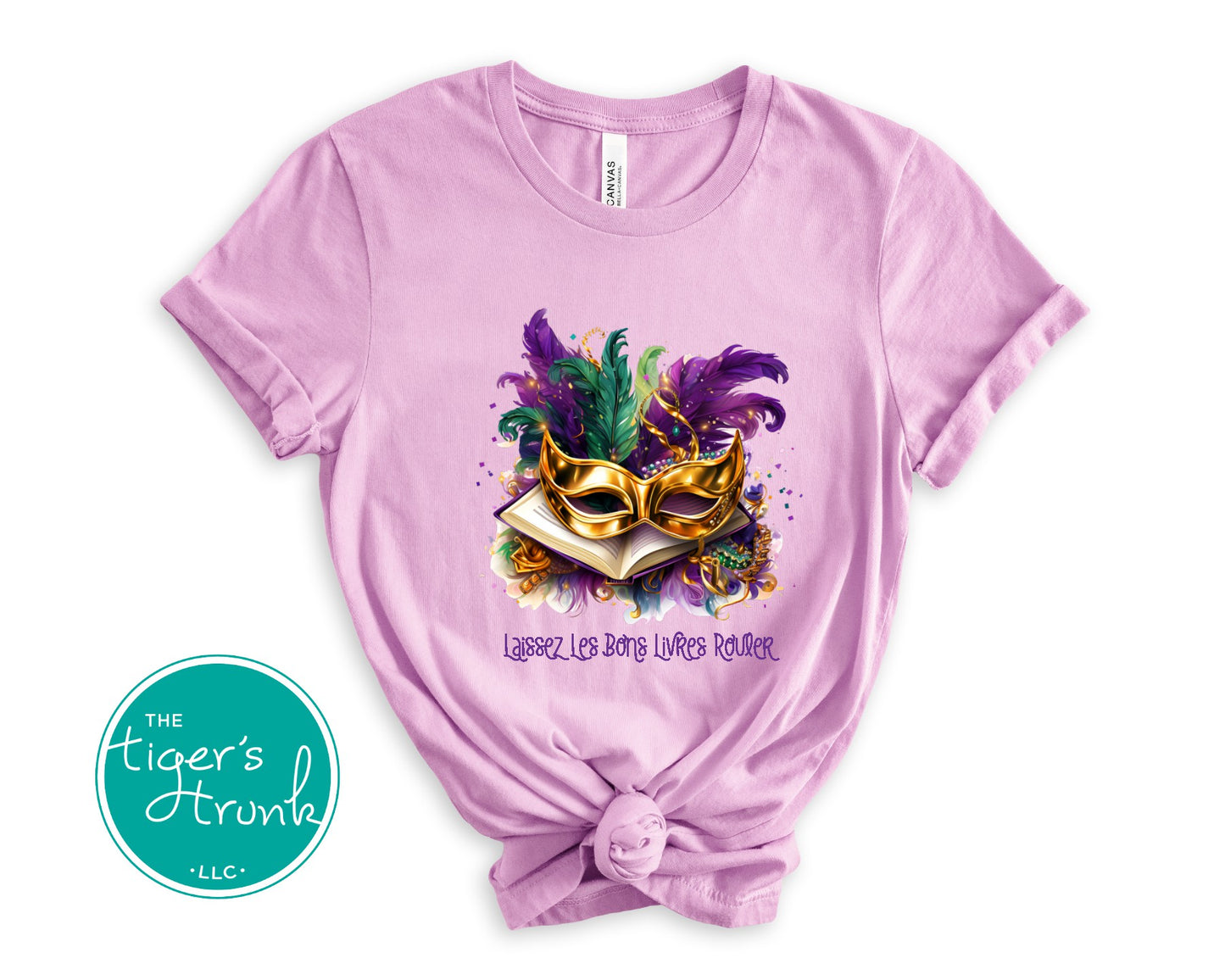 Mardi Gras shirt with books, masks, feathers, and beads, featuring the phrase "Laissez Les Bons Livres Rouler."