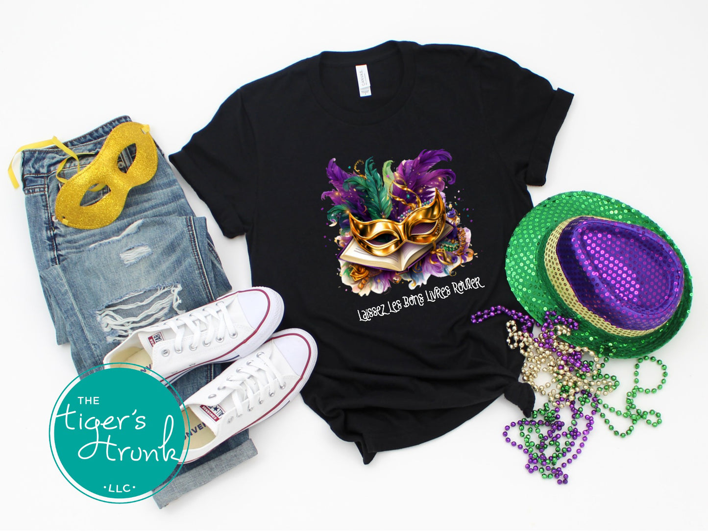 Mardi Gras shirt with books, masks, feathers, and beads, featuring the phrase "Laissez Les Bons Livres Rouler."