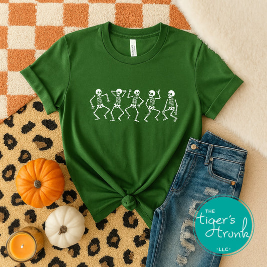 Green t-shirt with skeleton design on a leopard print surface with pumpkins and jeans.