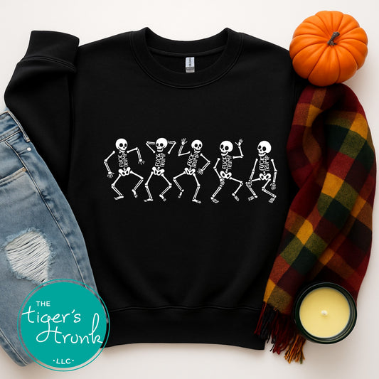 Black sweatshirt with skeleton design, surrounded by autumn-themed items on a white background.