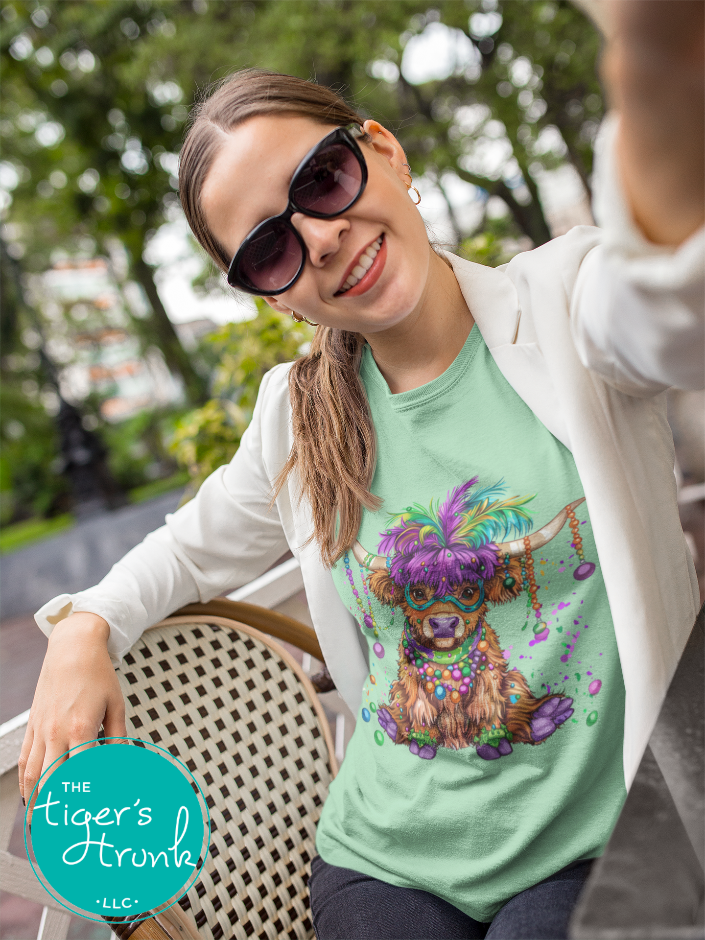 Mardi Gras t-shirt featuring a watercolor heifer adorned with colorful feathers and beads, perfect for festive celebrations.