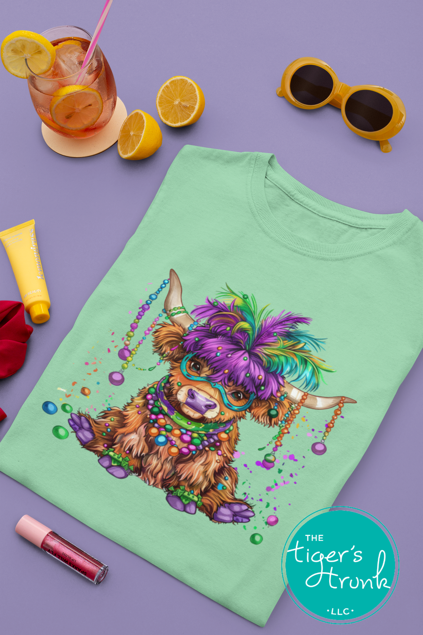 Mardi Gras t-shirt featuring a watercolor heifer adorned with colorful feathers and beads, perfect for festive celebrations.