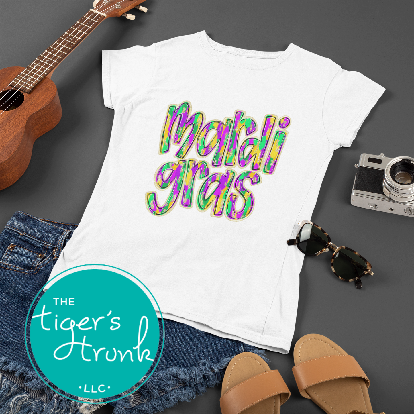 Mardi Gras t-shirt and muscle tank with hand-drawn paintbrush font in purple, green, and gold, perfect for festivals, parades, and celebrations.