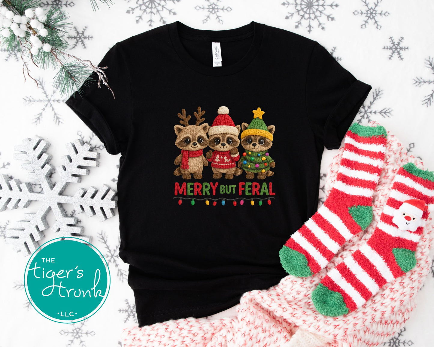 Black t-shirt with Christmas-themed design featuring three animals wearing hats and scarves, surrounded by festive decorations.