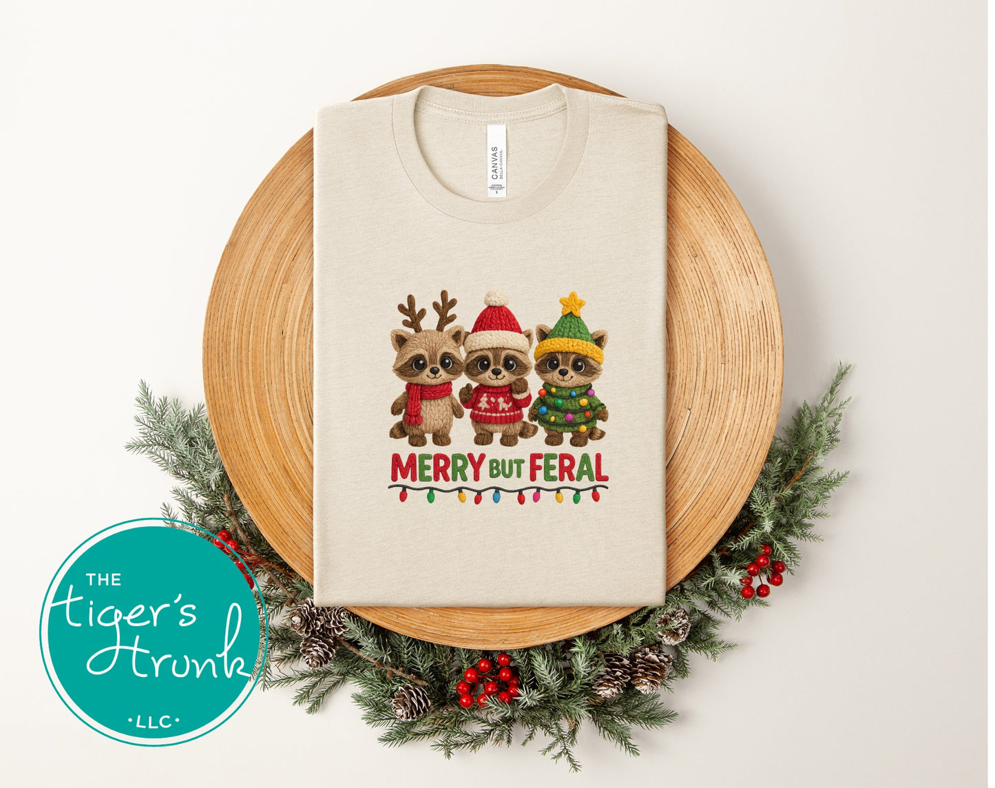Beige t-shirt with Christmas-themed design of three raccoons on a wooden board with decorative elements.