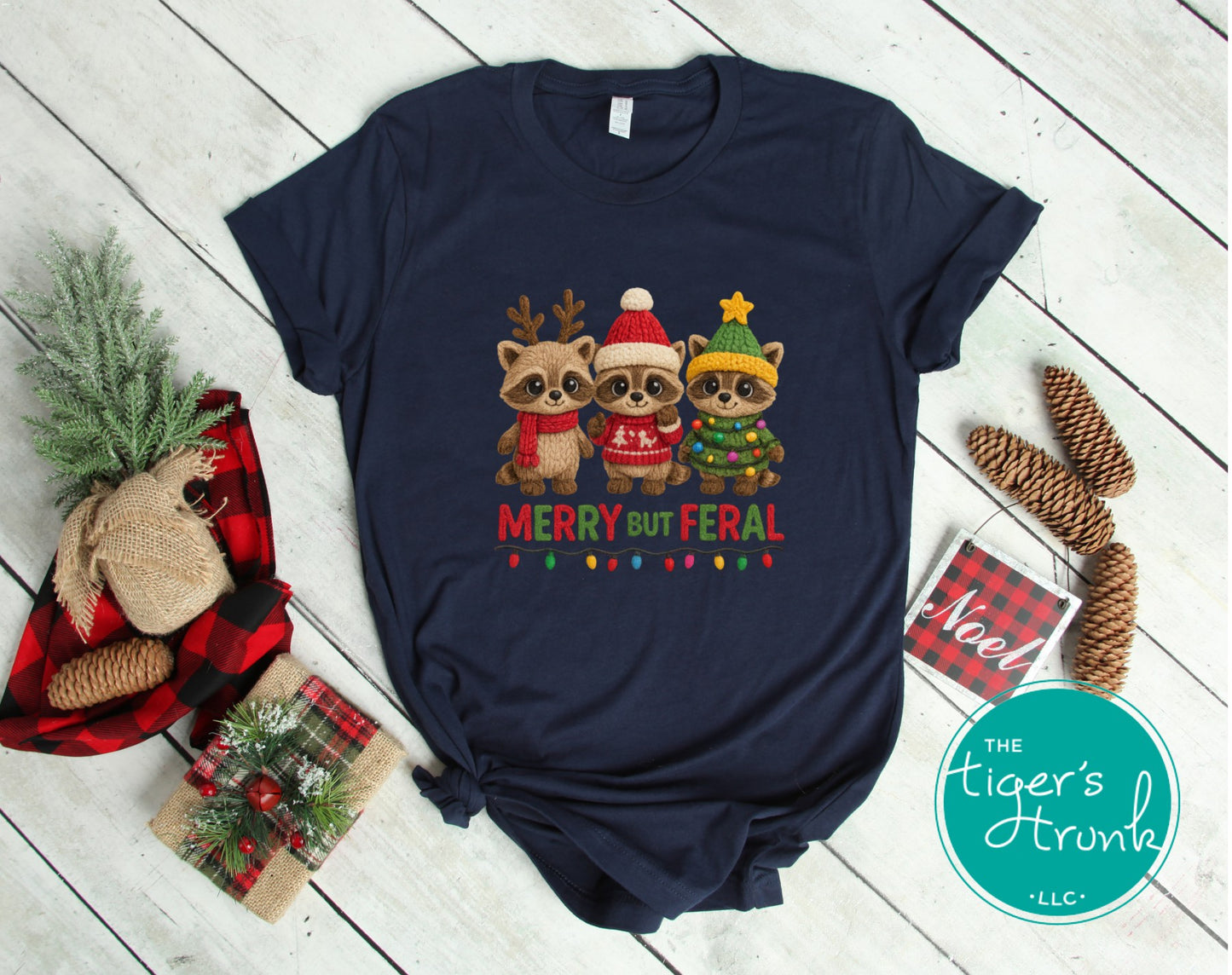 Navy blue t-shirt with Christmas-themed design featuring three raccoons on a wooden surface.