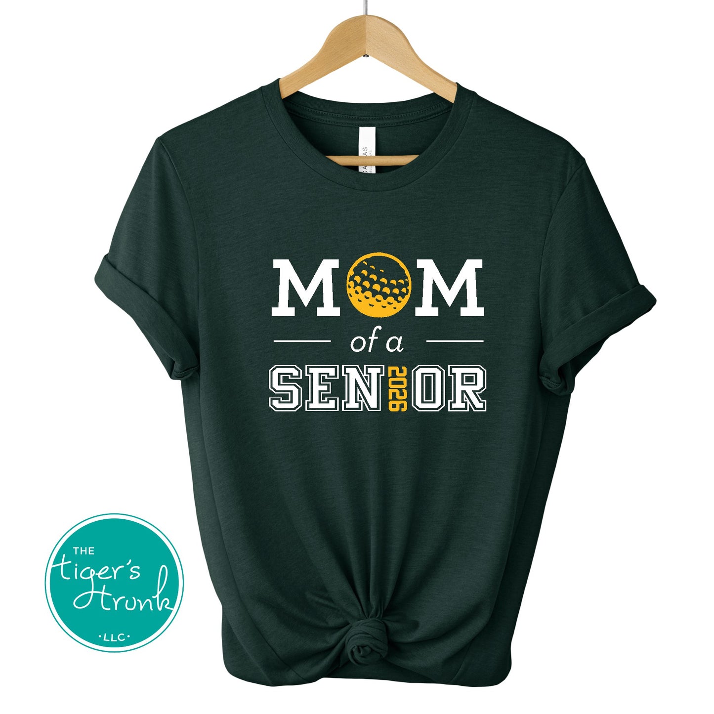 Green t-shirt with 'Mom of a Senior' text and a golf ball graphic on a hanger, branded with 'The Tiger's Trunk'.
