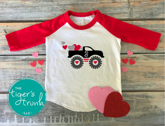 Valentine’s Day raglan shirt for kids with a monster truck and hearts design, personalized with a patchwork initial, available in three colors.