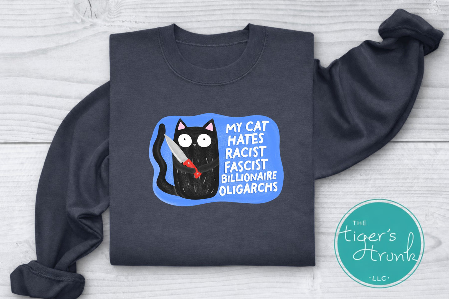 Dark gray sweatshirt with a graphic of a cat and text on a light wooden surface, featuring the brand 'The Tiger's Trunk'.