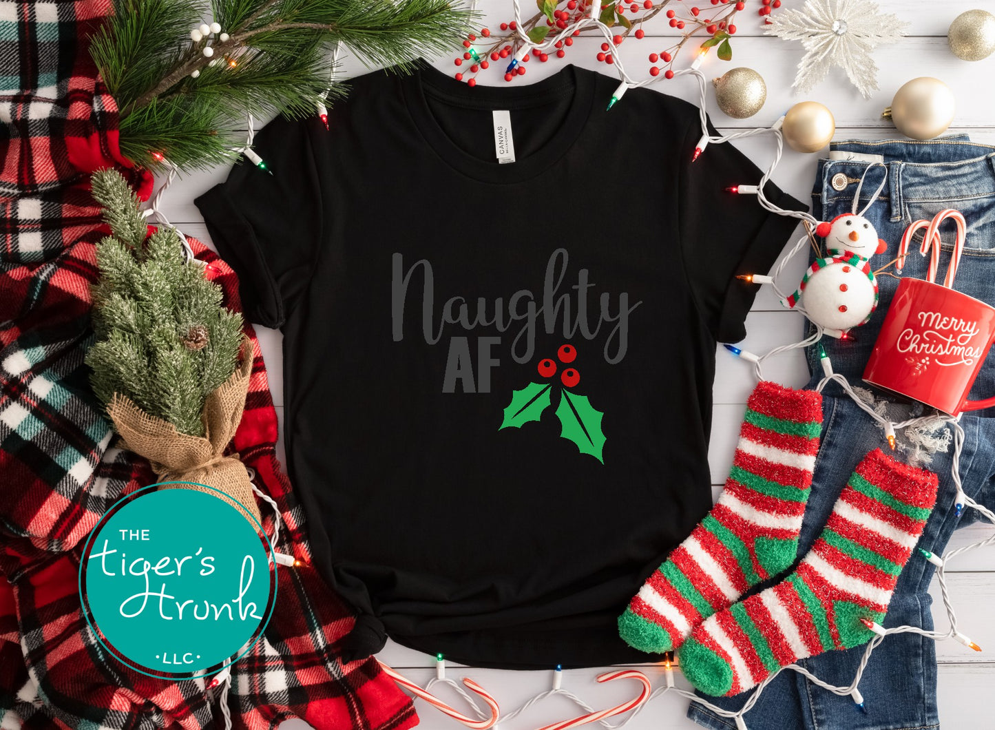 Black t-shirt with 'Naughty AF' text, surrounded by Christmas decorations including stockings and lights.