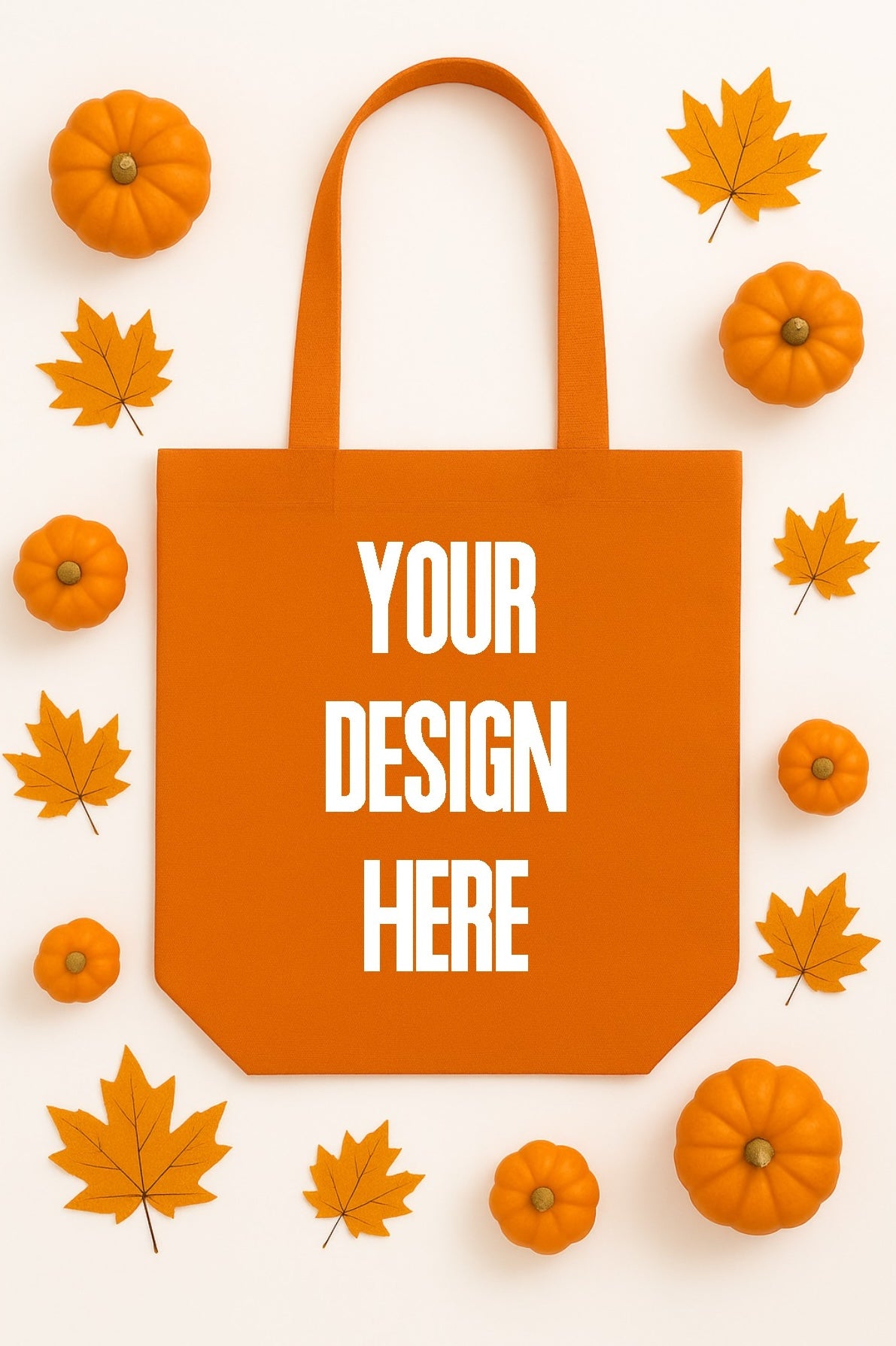 Orange tote bag with 'Your Design Here' text, surrounded by pumpkins and leaves on a white background
