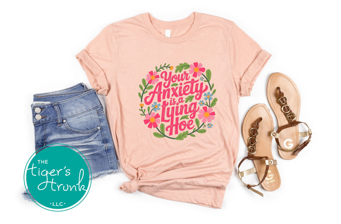 Peach graphic anxiety shirt styled with sandals and denim shorts featuring colorful floral artwork