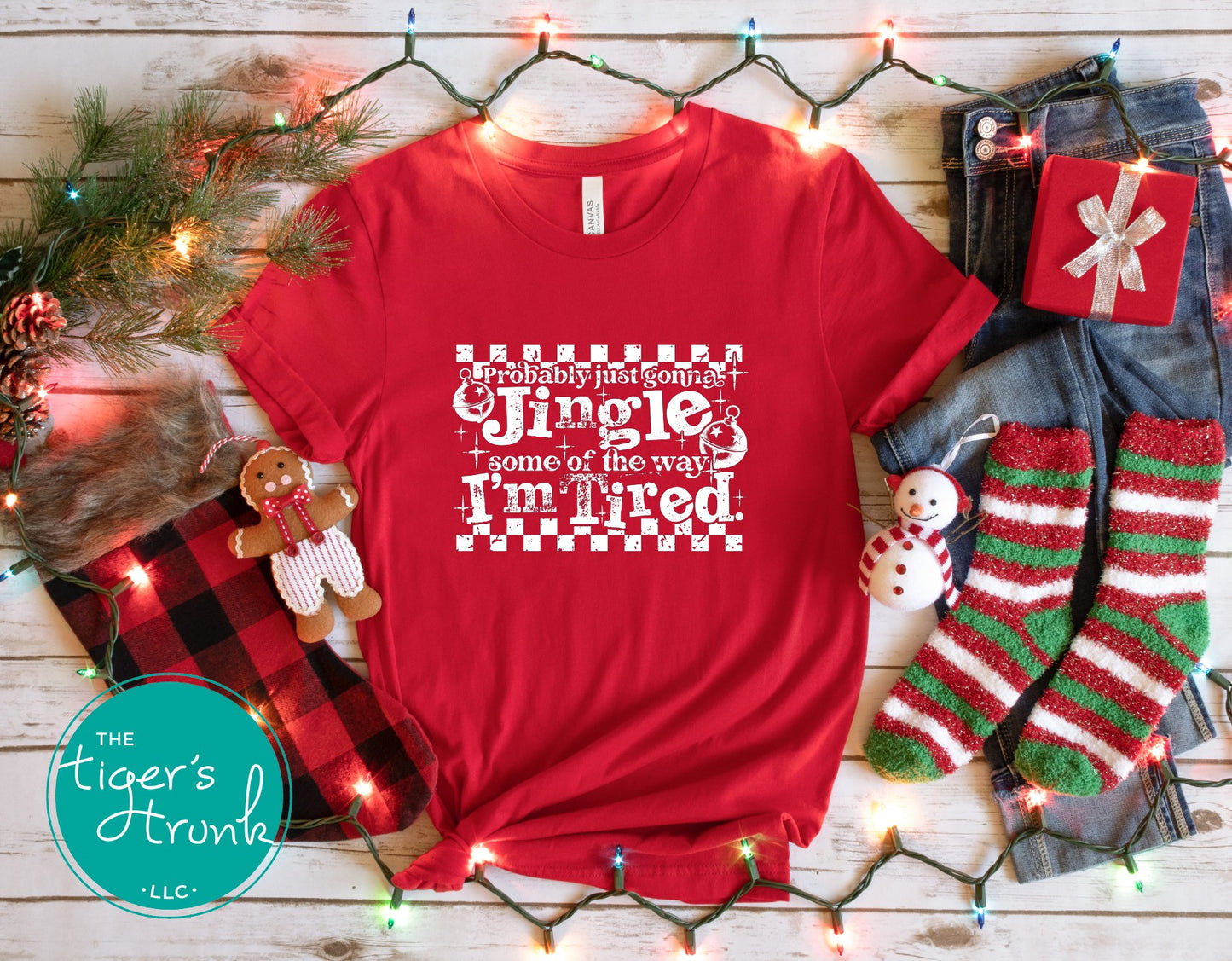 Red t-shirt with Christmas-themed design on a wooden surface with festive decorations.