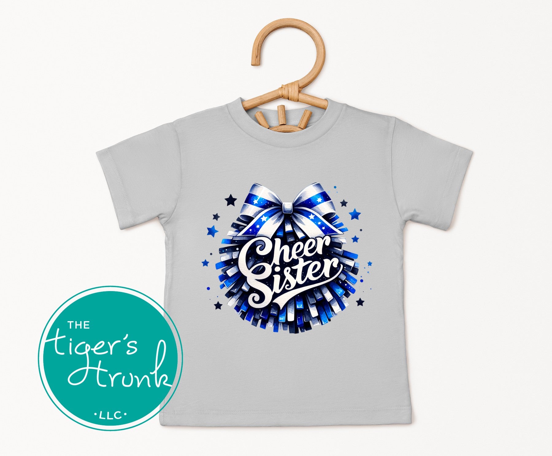 Gray t-shirt with 'Cheer Sister' design on a hanger, featuring The Tiger's Trunk LLC logo.