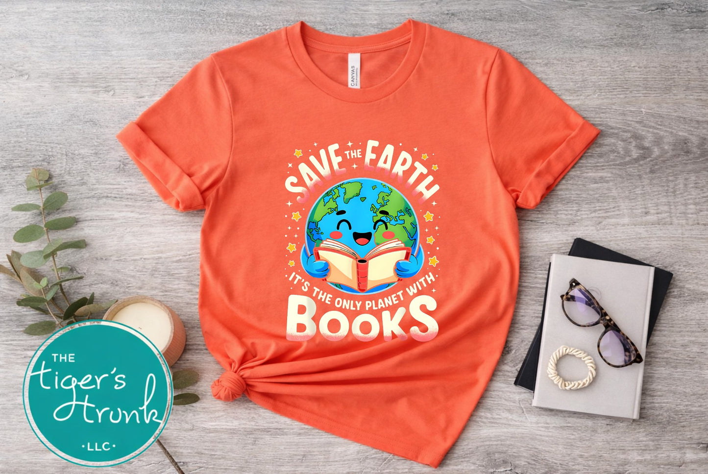 Orange t-shirt with 'Save the Earth, It's the Only Planet with Books' design on a wooden surface.