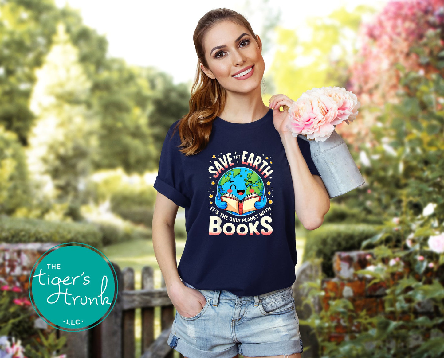 Woman wearing a navy blue t-shirt with an environmental message, holding flowers in a garden.